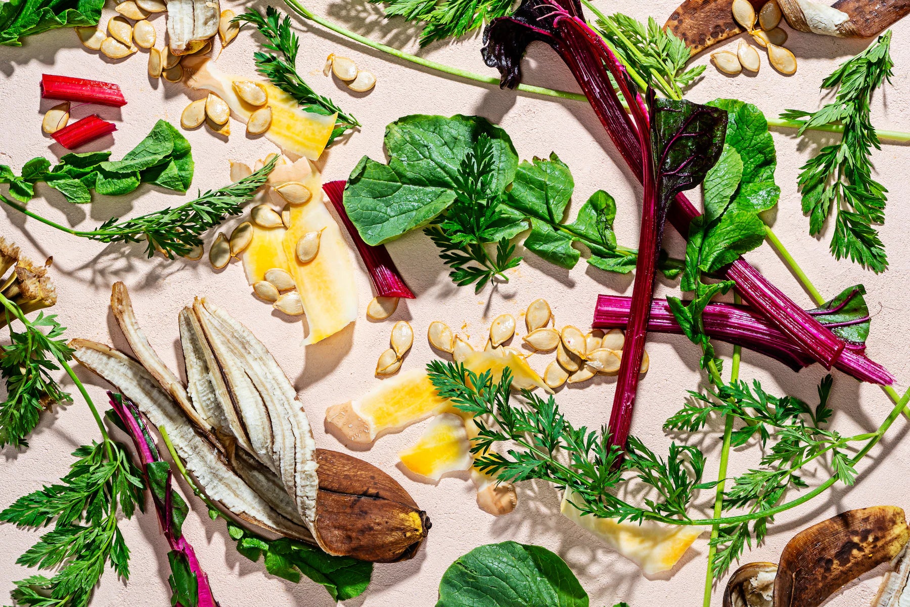 Assorted fresh vegetables and nuts on a light pink background