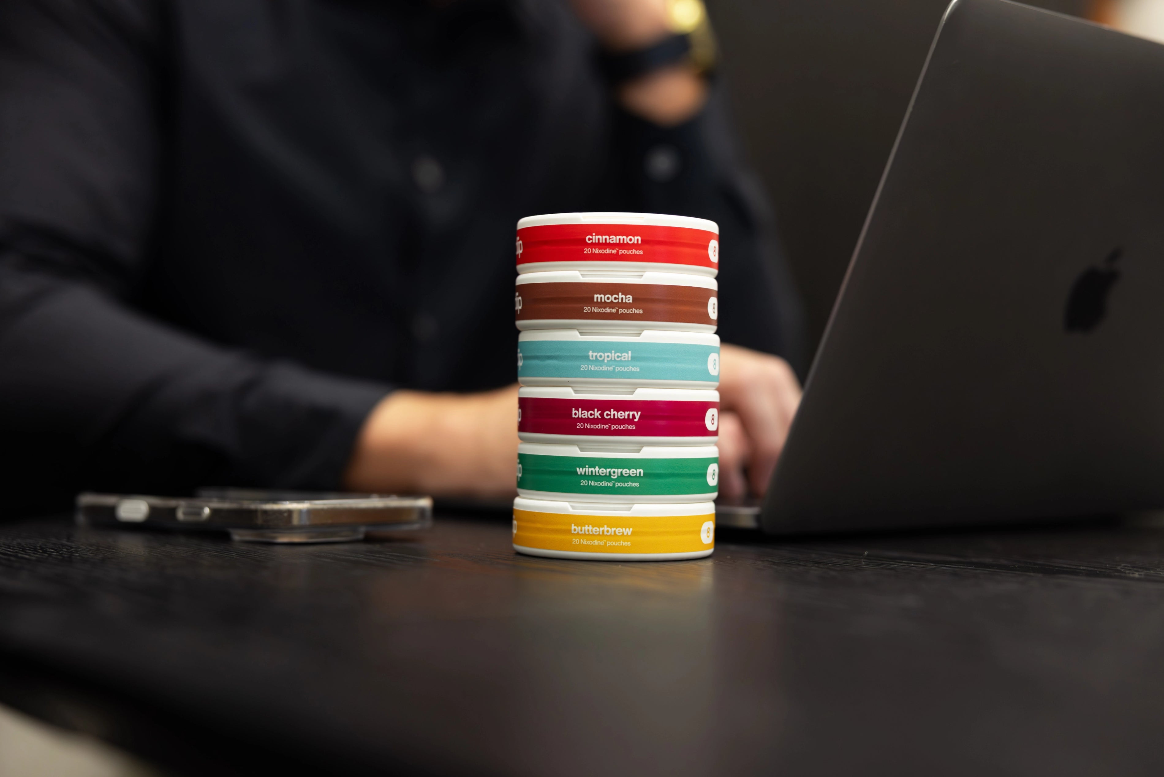 Collection of 'diip' branded nicotine-free dip pouch cans on grass with a hand placed next to them