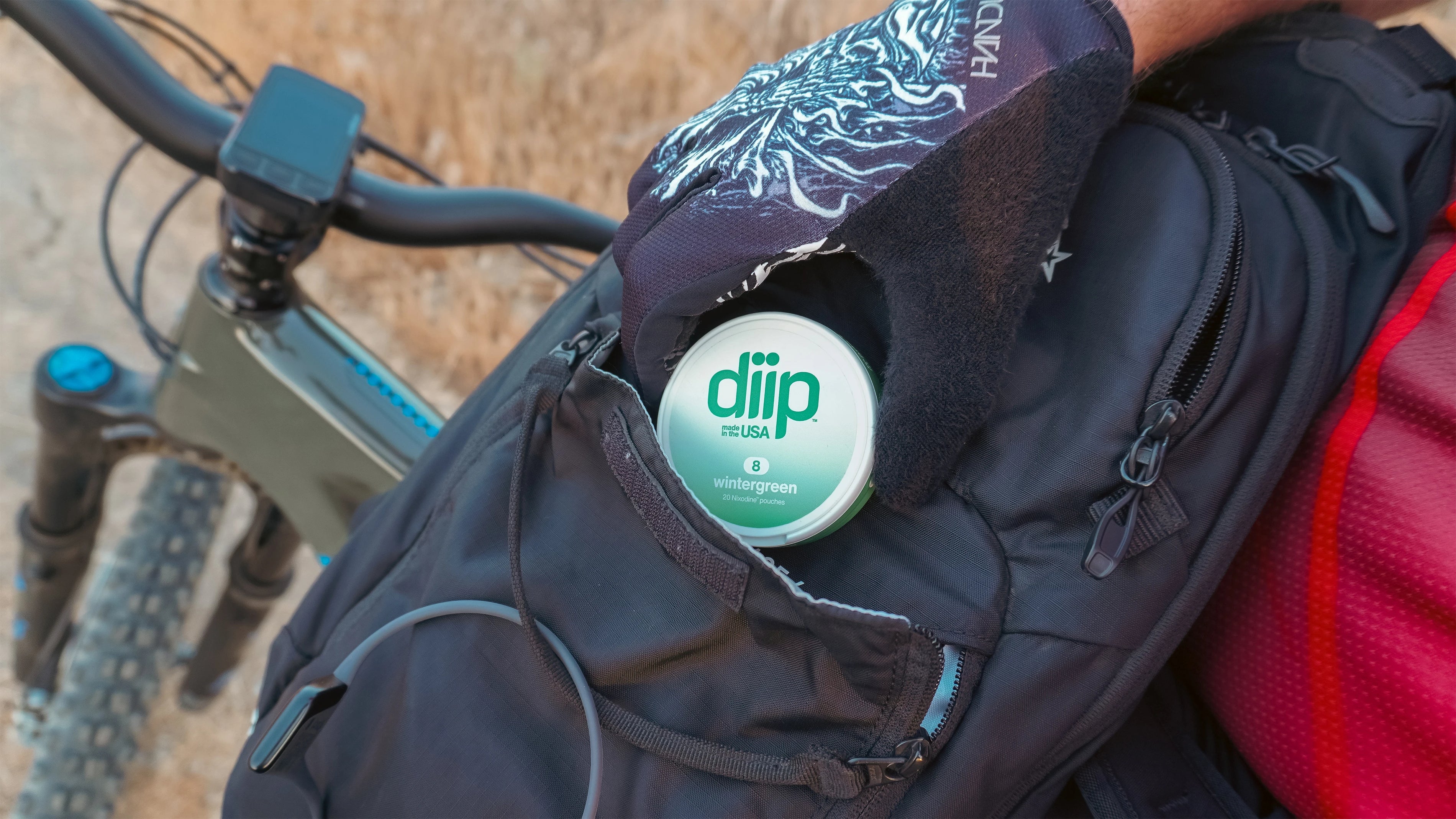 'Diip' branded 8 wintergreen nicotine-free dip pouch can in a backpack with a bicycle in the background