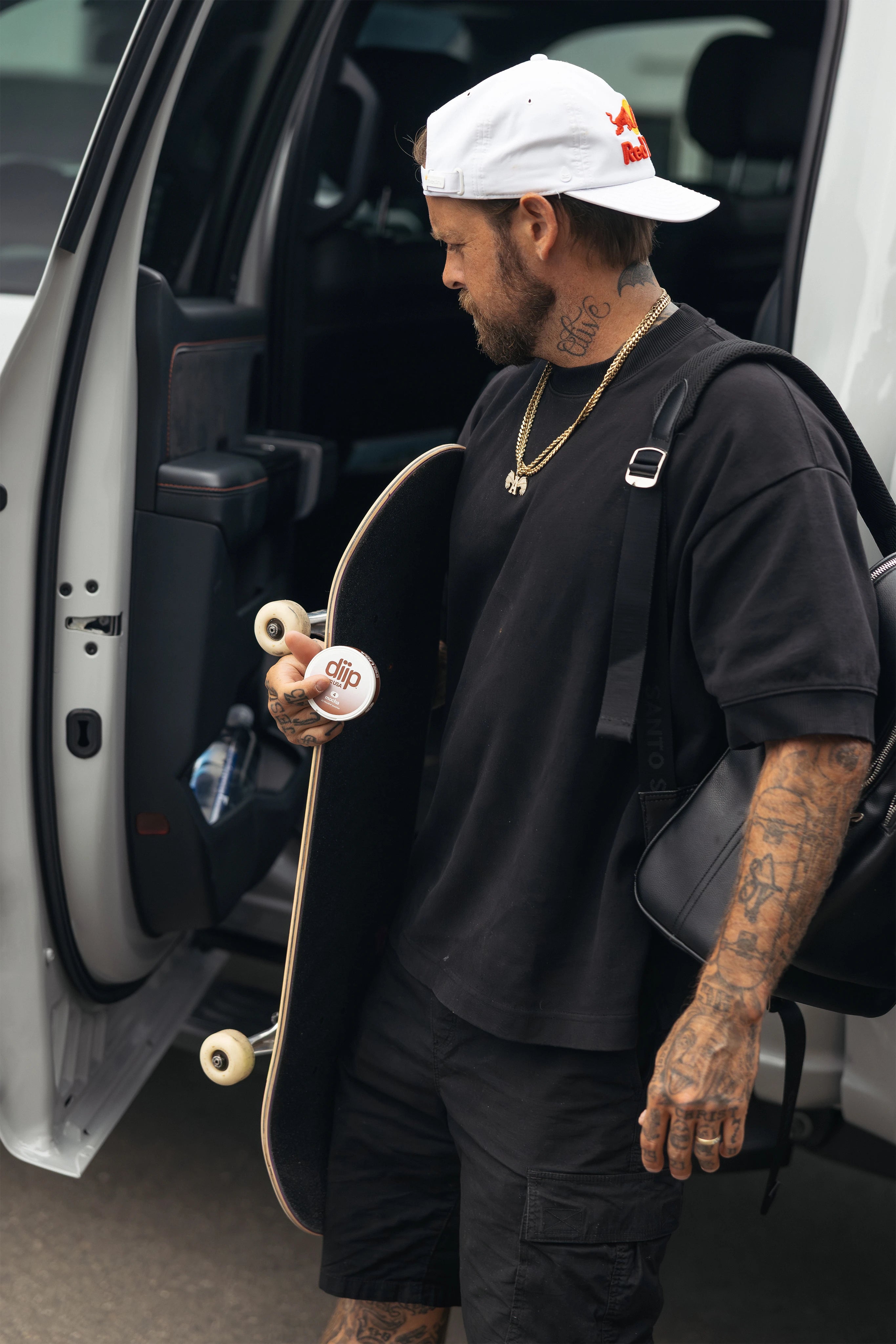 Ryan Sheckler holding a skateboard and a 'diip' branded 4 mocha nicotine-free dip pouch can next to an open truck door