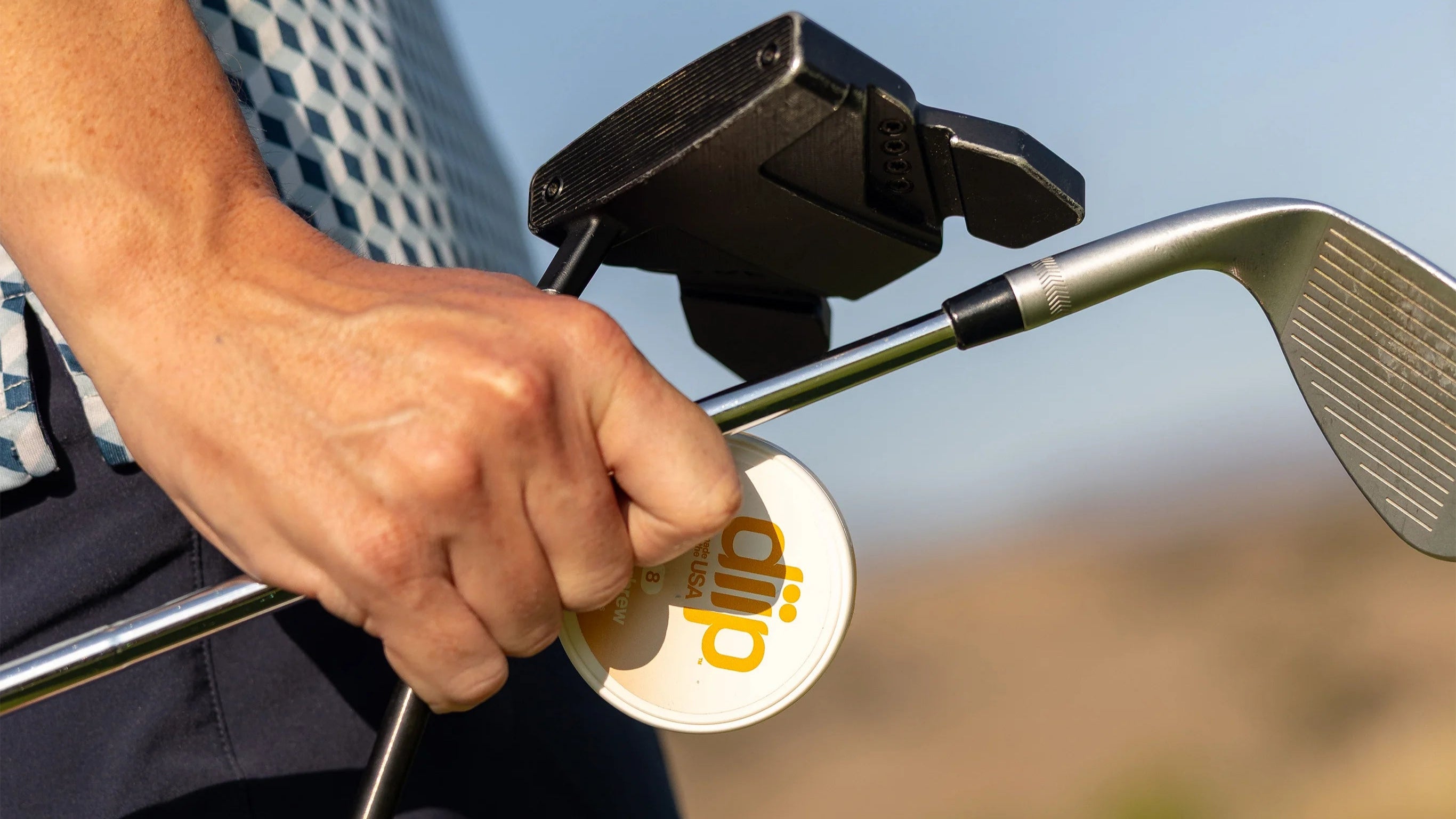 Man holding golf clubs and a 'diip' branded 8 butterbrew nicotine-free dip pouch can on a golf course