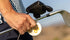Man holding golf clubs and a 'diip' branded 8 butterbrew nicotine-free dip pouch can on a golf course